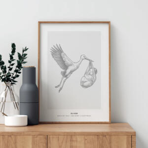 En stilren poster i ram med motivet "White Storch" från Stories by Mia, som föreställer en elegant illustration av en stork som flyger och bär ett lindat nyfött barn i näbben. Postern är personlig och innehåller barnets namn samt födelsedetaljer som datum, tid, vikt och längd. Tavlan är placerad på en träbänk, omgiven av minimalistisk inredning i en modern, skandinavisk stil.